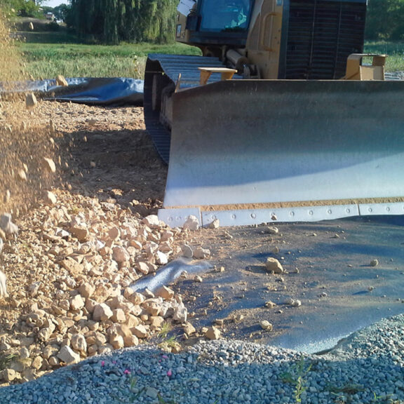 Adding stone on top of a woven geotextile.