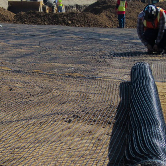 Construction professionals installing uniaxial geogrids