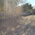 An earthen drainage channel with eroding slopes at Blossom Park in San Antonia, Texas.