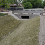 A concrete drainage channel with HardArmor reinforcement and vegetated HPTRMs.