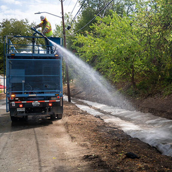 Hydrating the newly installed concrete canvas ditch liner to improve drainage and prevent erosion.