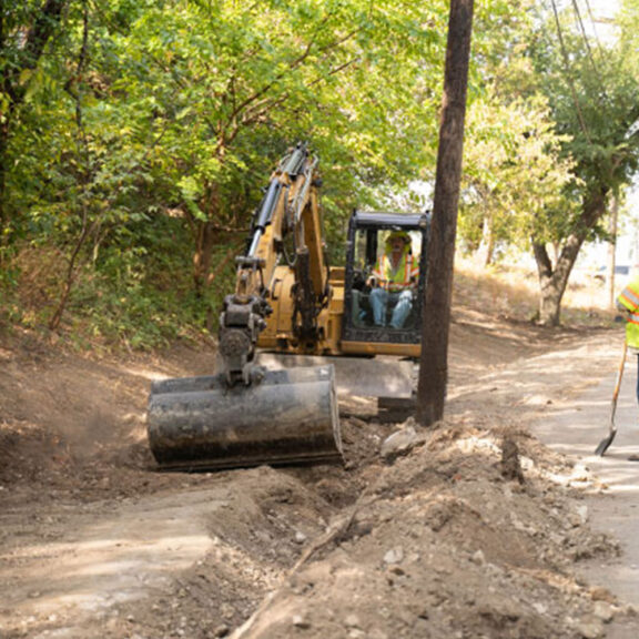 Removing debris before installing concrete canvas ditch lining.