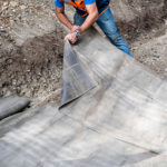 Installing pre-cut concrete fabric in a ditch to create a durable lining.