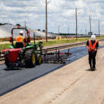 Large equipment pouring asphalt over milled pavement to repair reflective cracking.