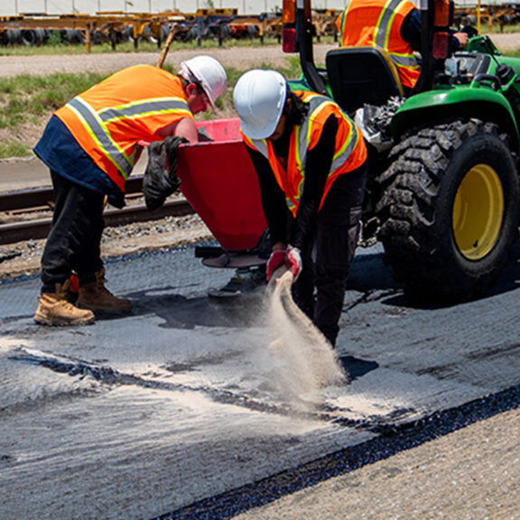 Asphalt repair workers fixing reflective cracks on the Union Pacific Railroad.